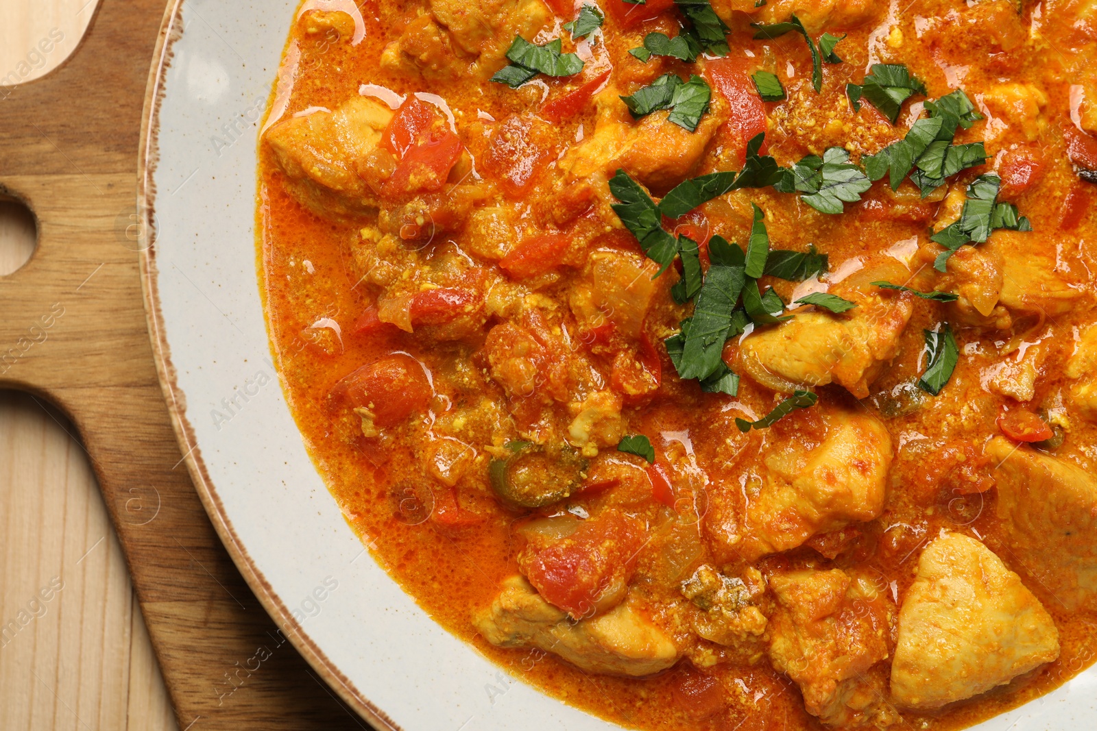 Photo of Delicious chicken curry on wooden table, top view