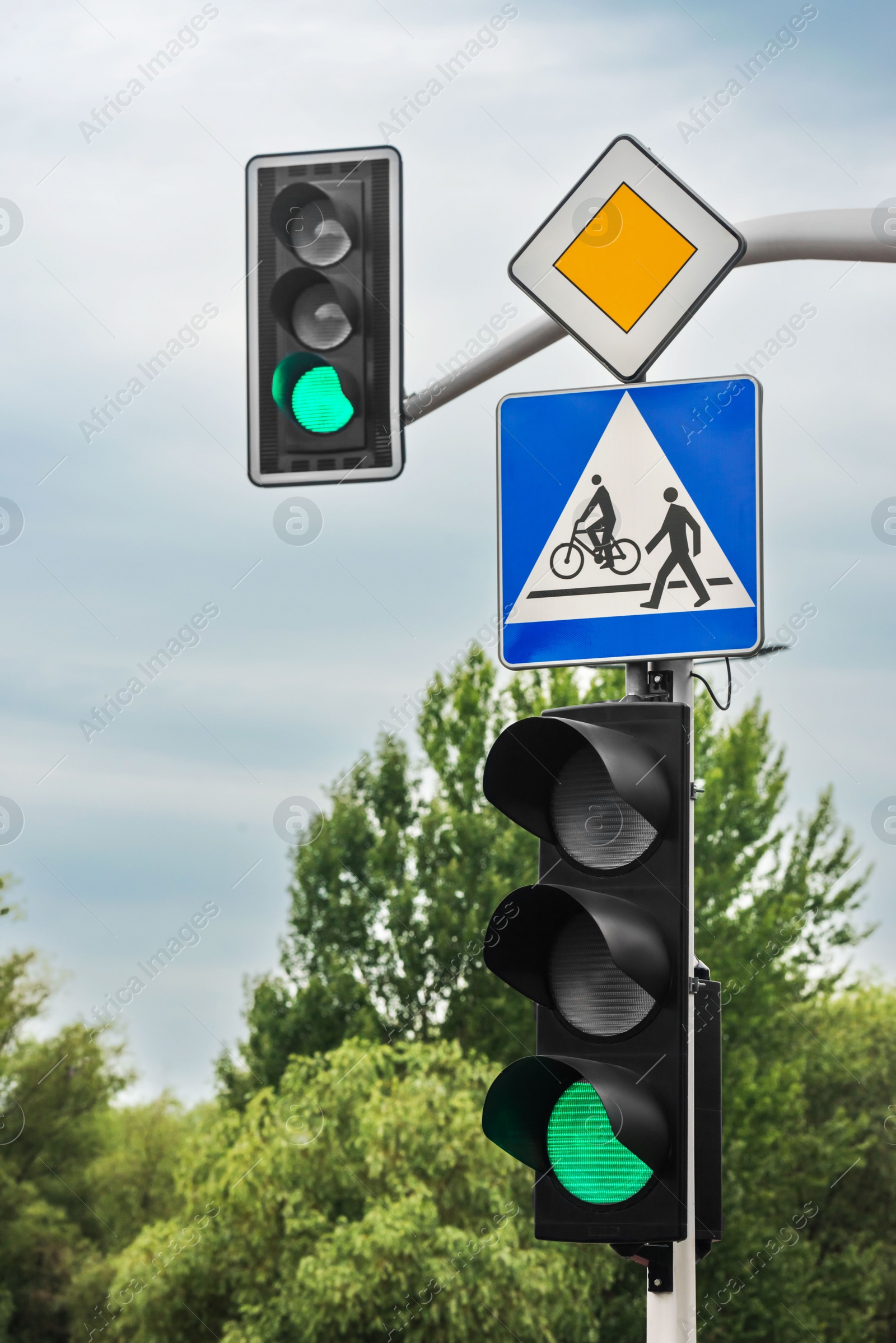 Photo of Post with Priority Road and Pedestrian crossing signs near traffic lights outdoors