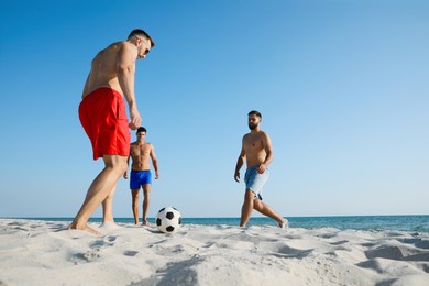 Group of friends playing football on beach