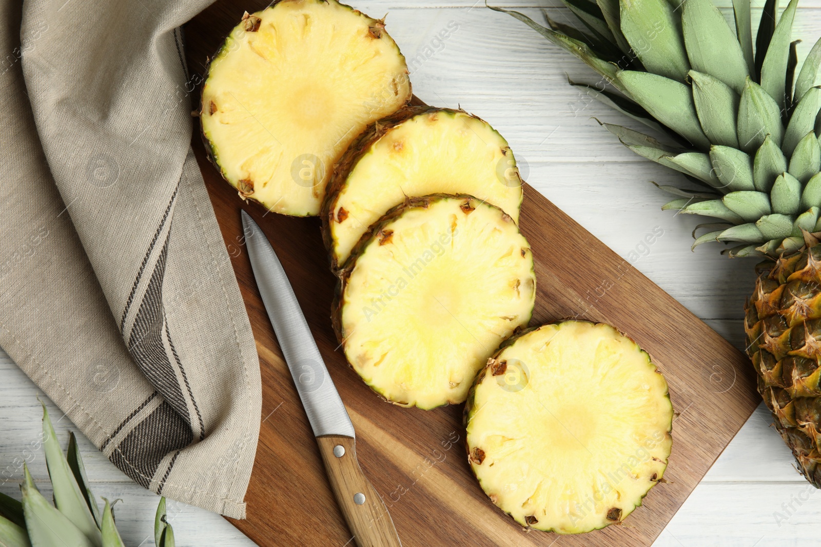 Photo of Slices of fresh pineapple on white wooden table, flat lay