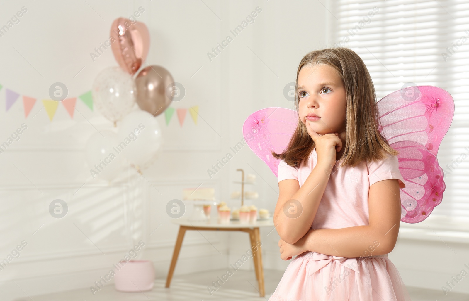 Photo of Cute little girl wearing fairy costume with wings in decorated room. Space for text