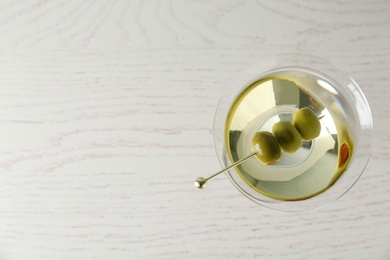 Glass of Classic Dry Martini with olives on wooden table, top view. Space for text