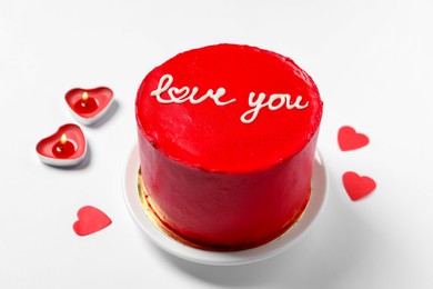 Photo of Bento cake with text Love You, candles and paper hearts on white table. St. Valentine's day surprise