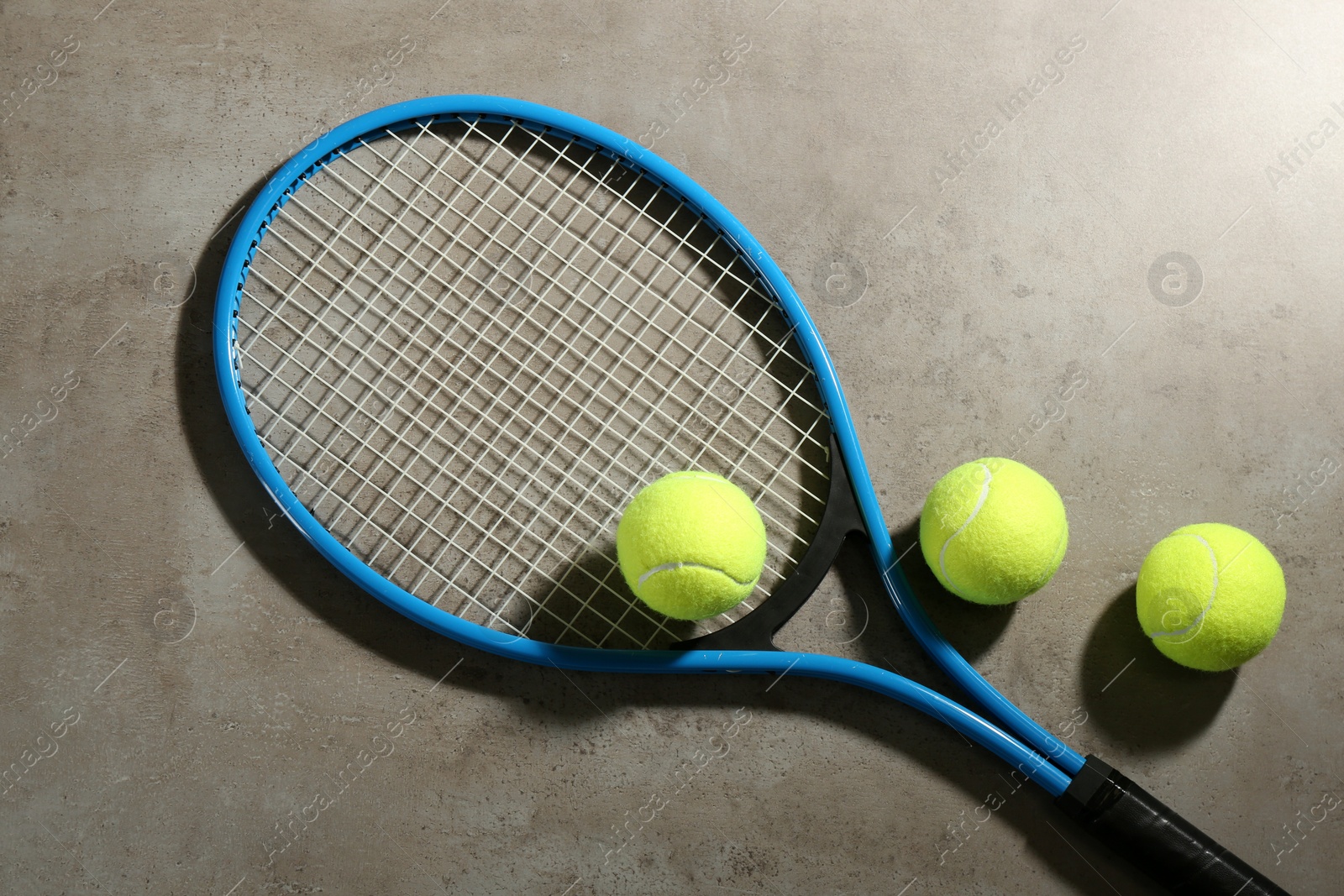 Photo of Tennis racket and balls on grey table, flat lay. Sports equipment