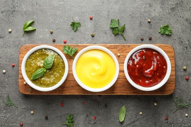 Set of different delicious sauces on grey table, top view