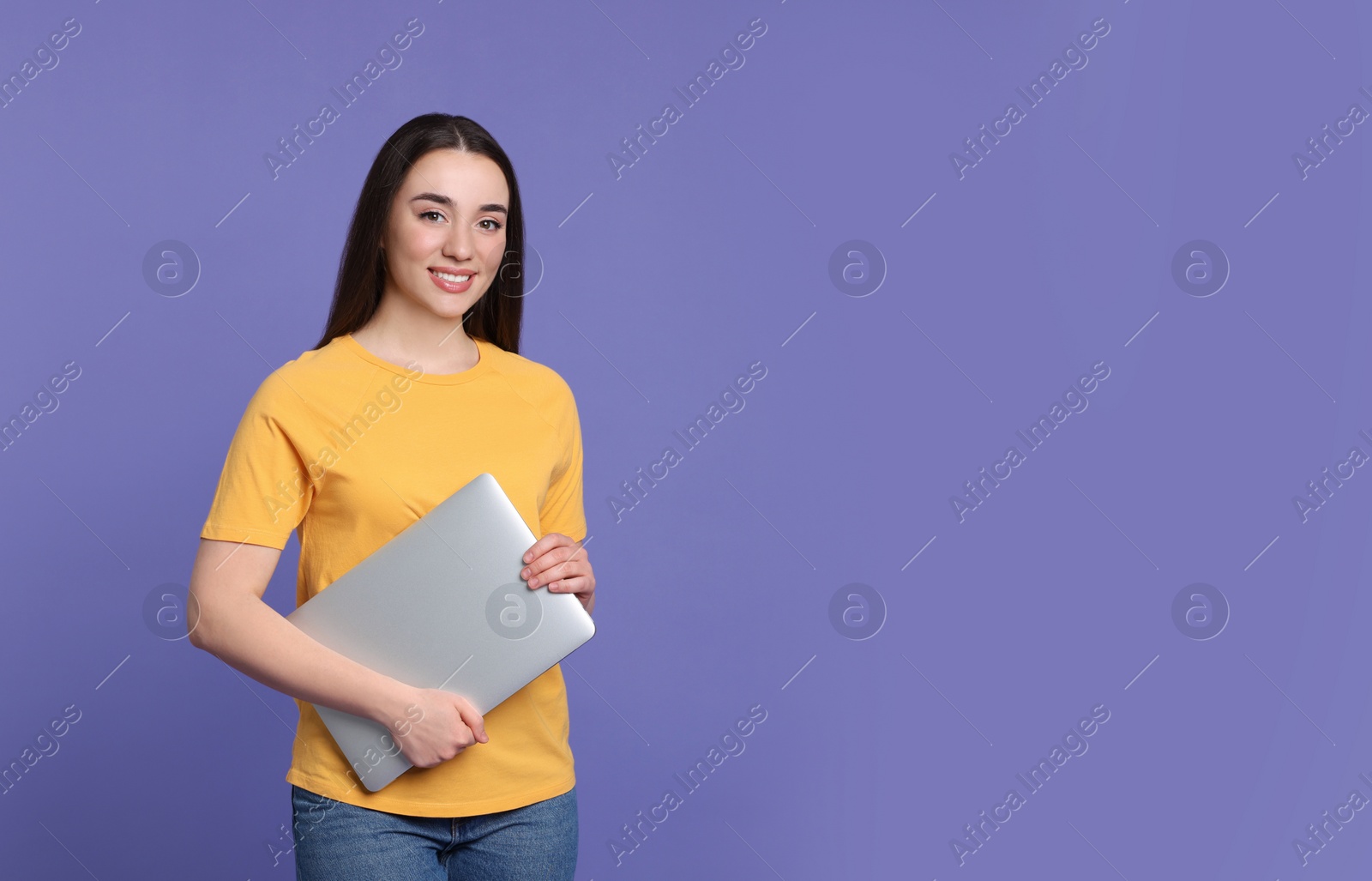 Photo of Smiling young woman with laptop on lilac background, space for text