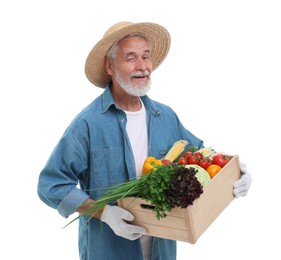 Photo of Harvesting season. Happy farmer holding wooden crate with vegetables and winking on white background