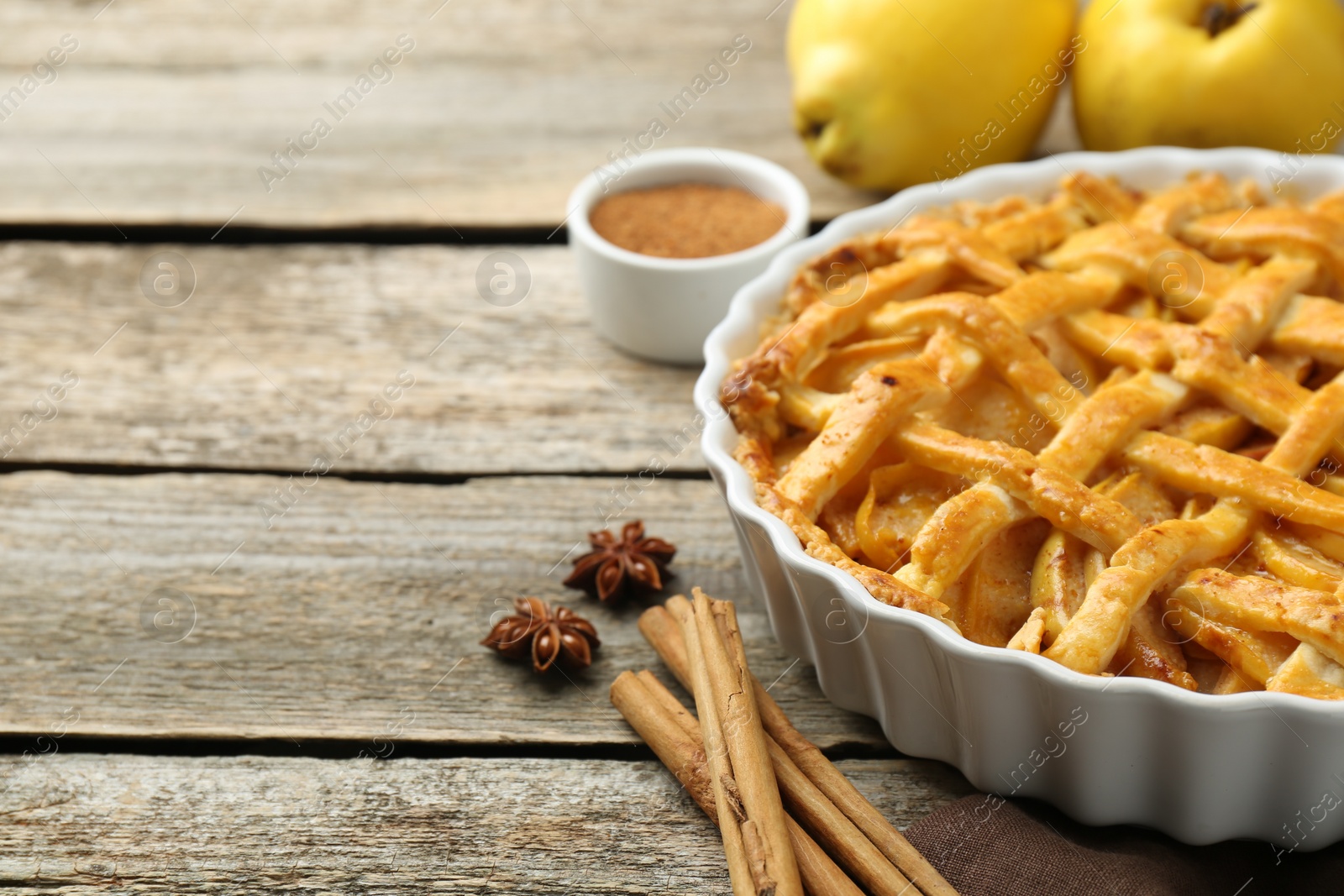 Photo of Tasty homemade quince pie with spices on wooden table. closeup. Space for text