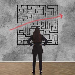 Image of Businesswoman looking at wall with illustration of maze indoors