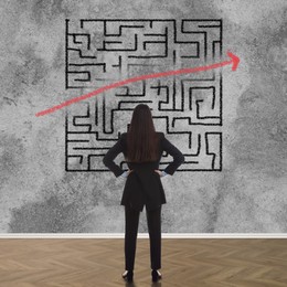 Businesswoman looking at wall with illustration of maze indoors