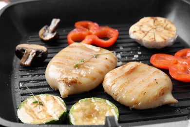 Photo of Cooking fresh squid tubes with vegetables and mushroom on grill pan, closeup