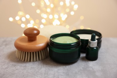 Photo of Natural scrub and other body care products on grey table against blurred lights