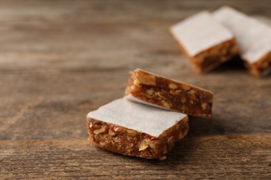 Photo of Pieces of tasty protein bar on wooden table. Space for text