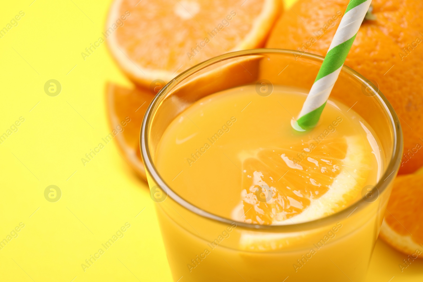 Photo of Glass of orange juice and fresh fruits on yellow background, closeup