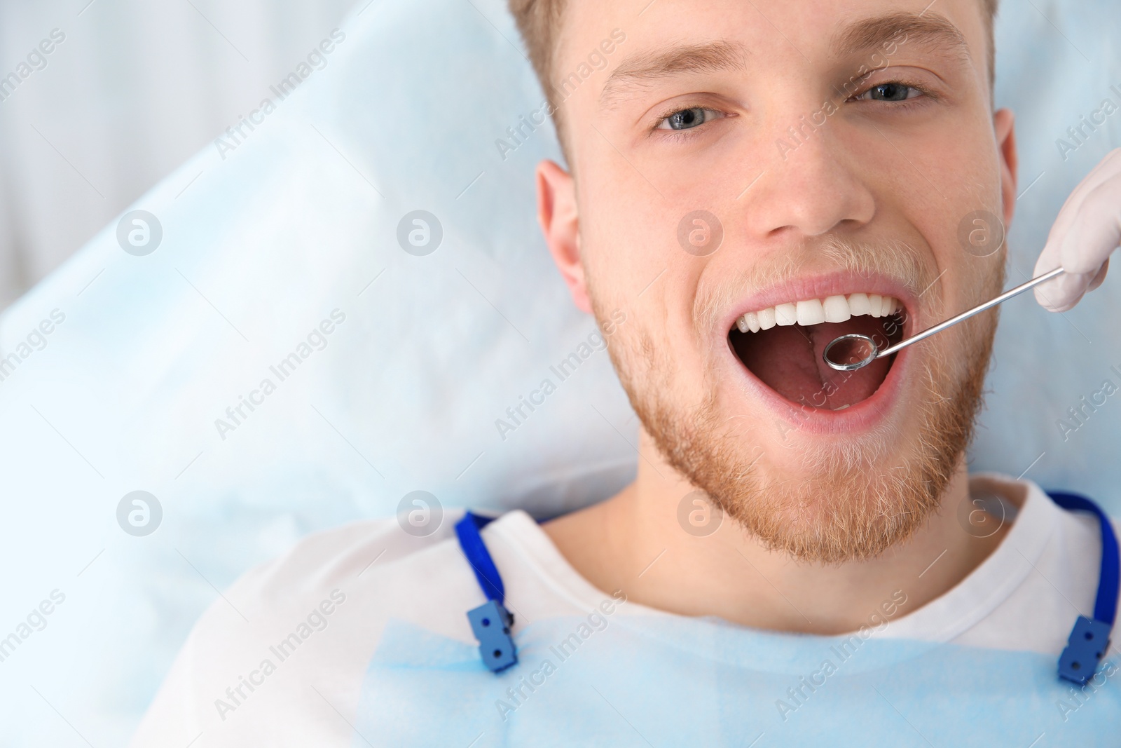 Photo of Dentist examining patient's teeth in modern clinic. Space for text