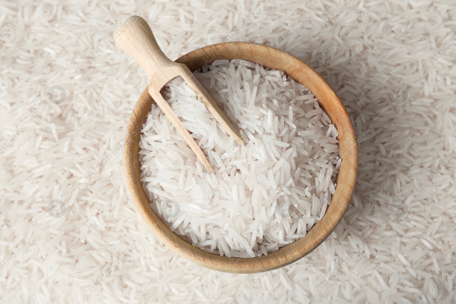 Photo of Raw basmati rice, bowl and scoop as background, top view