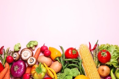 Flat lay composition with fresh vegetables on light pink background. Space for text