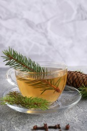 Photo of Cup with delicious immunity boosting tea and fir on grey table