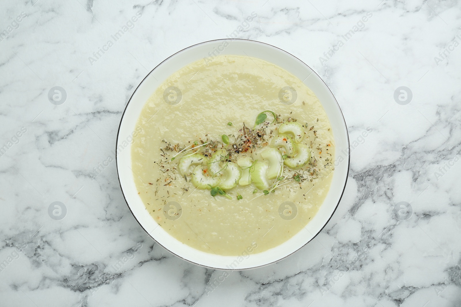 Photo of Bowl of delicious celery soup on white marble table, top view