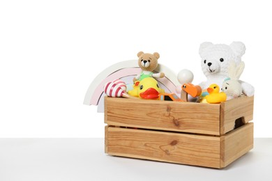 Photo of Wooden crate with different children's toys on table against white background, space for text