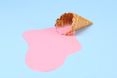 Photo of Melted ice cream and wafer cone on light blue background
