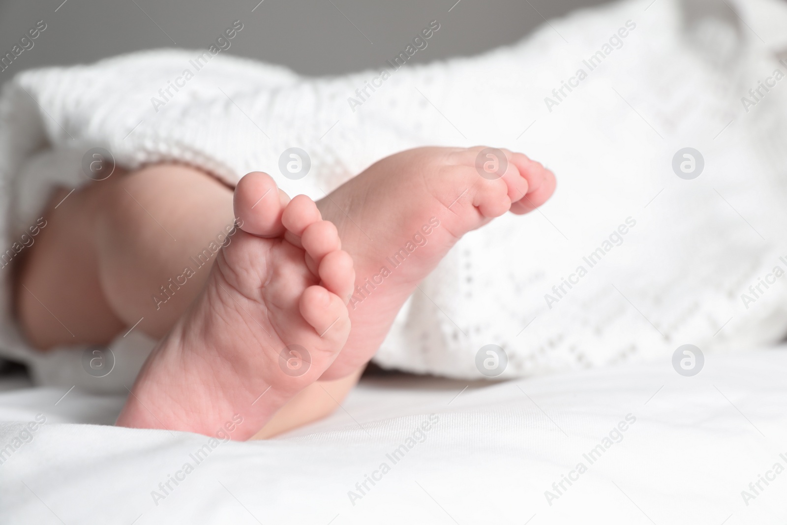 Photo of Little baby with cute feet lying on bed, closeup. Space for text