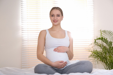 Young pregnant woman on bed at home