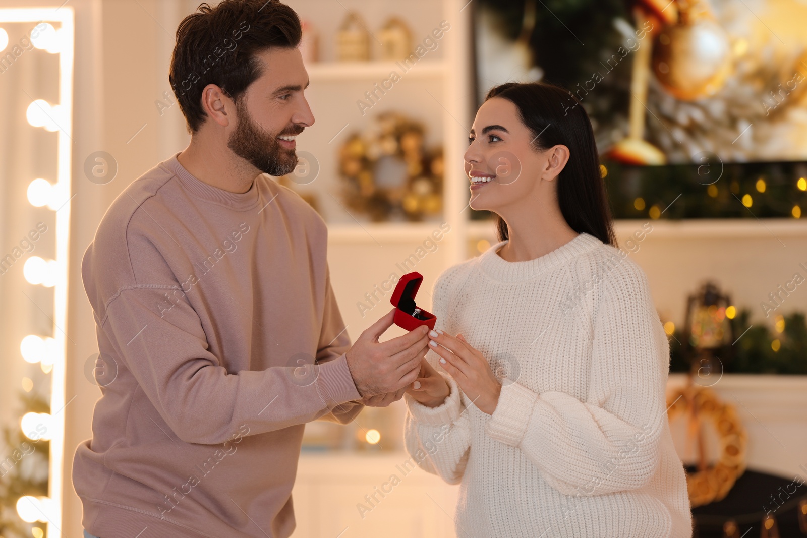 Photo of Making proposal. Man with engagement ring surprising his girlfriend at home on Christmas