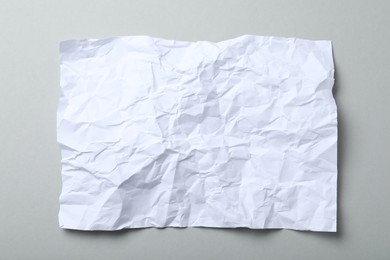 Photo of Sheet of white crumpled paper on grey background, top view