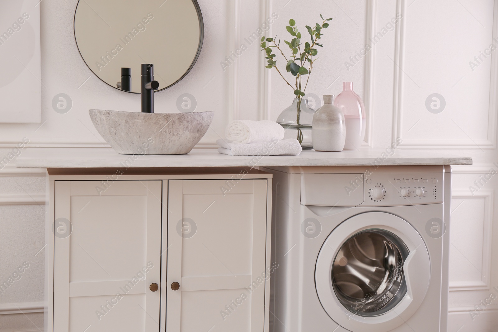 Photo of Laundry room interior with modern washing machine and stylish vessel sink on countertop