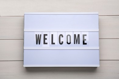 Lightbox with word Welcome on white wooden background, top view