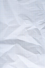 Crumpled checkered notebook sheet as background, top view