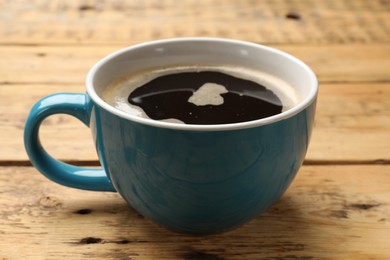 Cup of aromatic coffee on wooden table, closeup