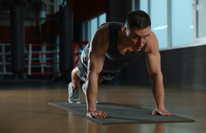 Photo of Man doing plank exercise in modern gym