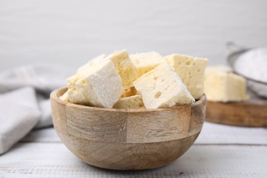 Photo of Bowl with tasty marshmallows on white wooden table, closeup