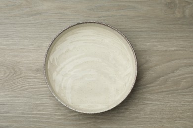 Beige bowl with water on wooden table, top view