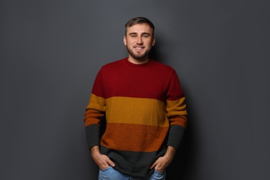 Photo of Handsome young man in warm sweater on dark background