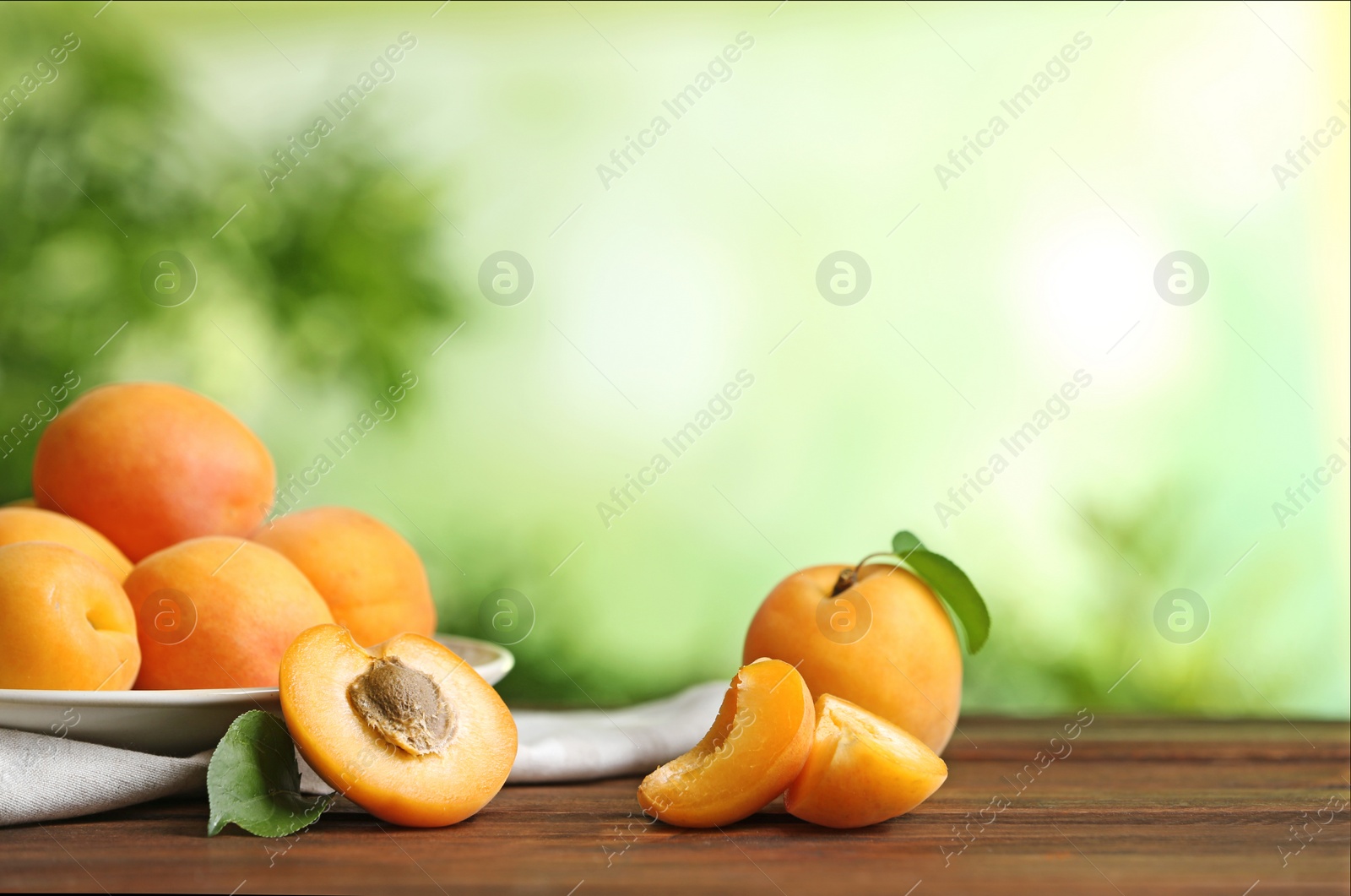 Photo of Delicious ripe sweet apricots on wooden table against blurred background, space for text