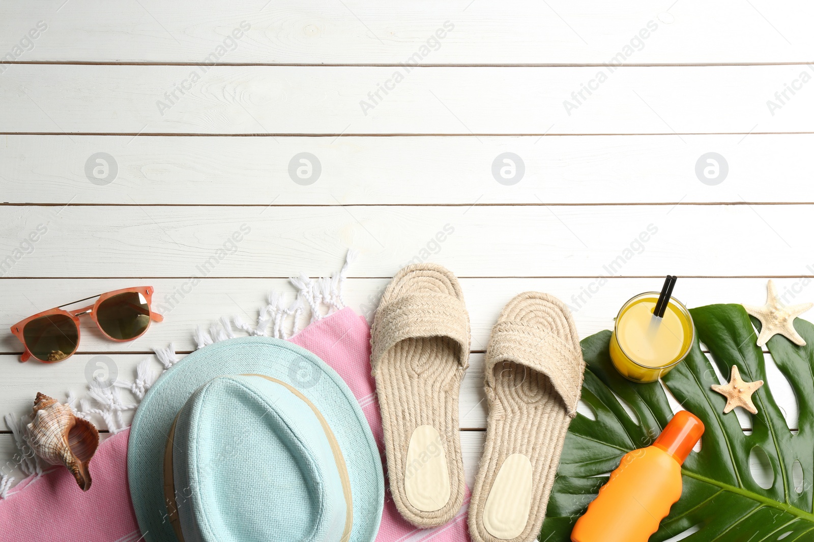 Photo of Beach accessories and drink on white wooden table, flat lay. Space for text