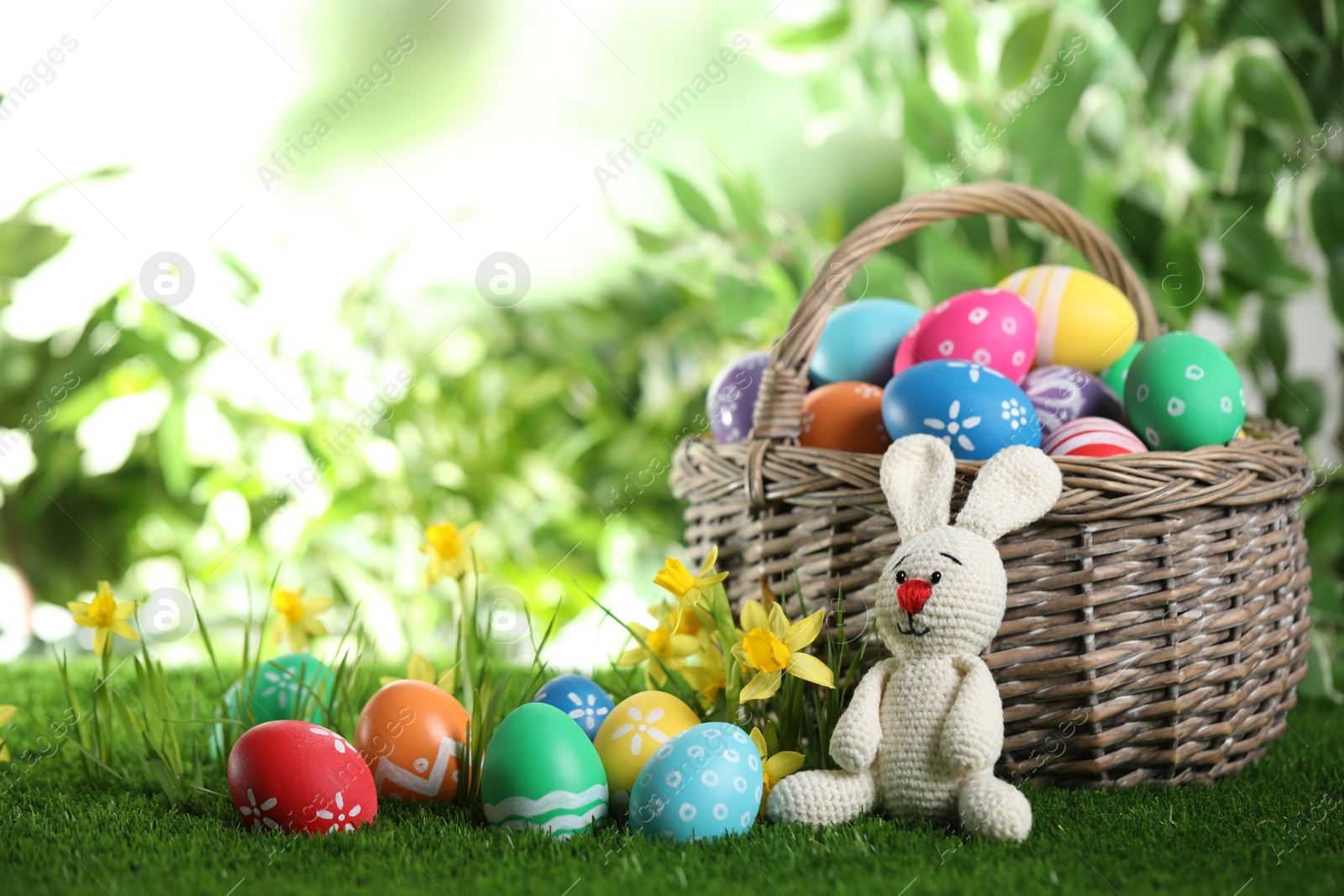 Photo of Colorful Easter eggs and toy rabbit on green grass. Space for text