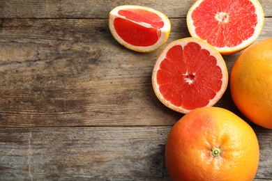 Fresh tasty grapefruits on wooden background, top view with space for text