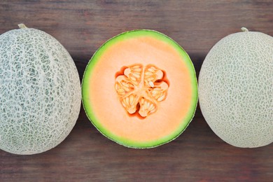 Whole and cut fresh ripe melons on wooden table, flat lay