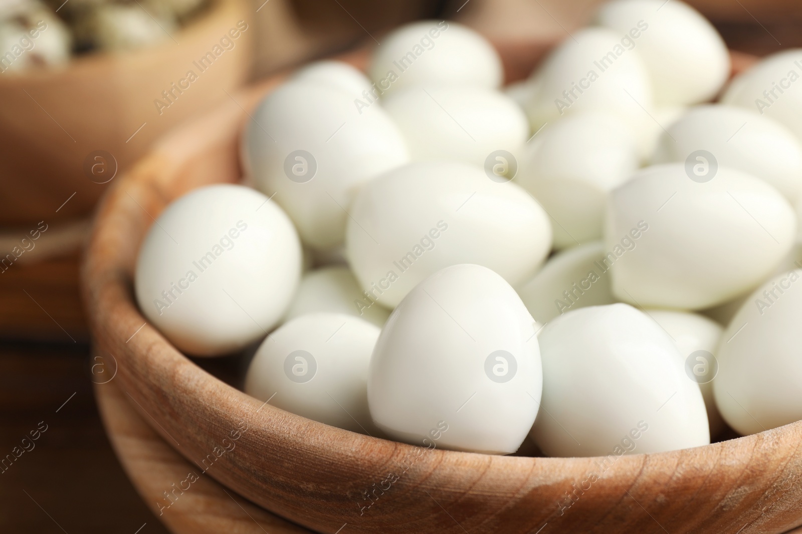 Photo of Peeled boiled quail eggs in wooden bowl, closeup