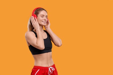 Sportswoman with headphones on yellow background, space for text
