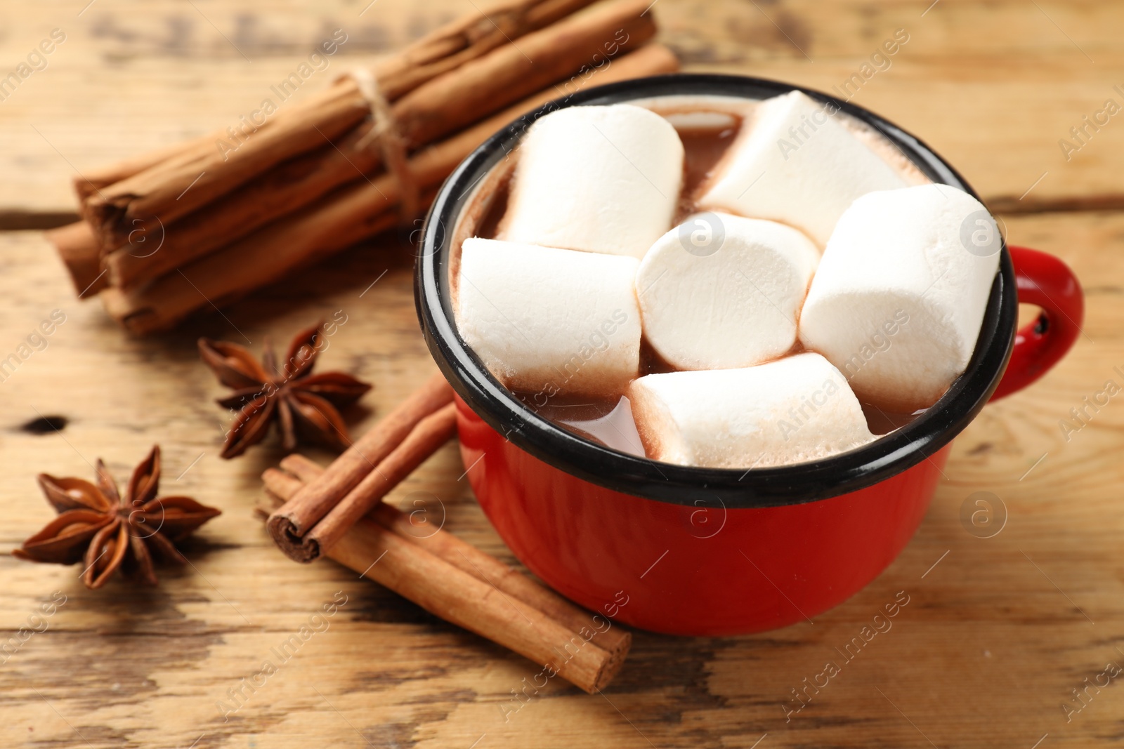 Photo of Tasty hot chocolate with marshmallows and spices on wooden table, closeup