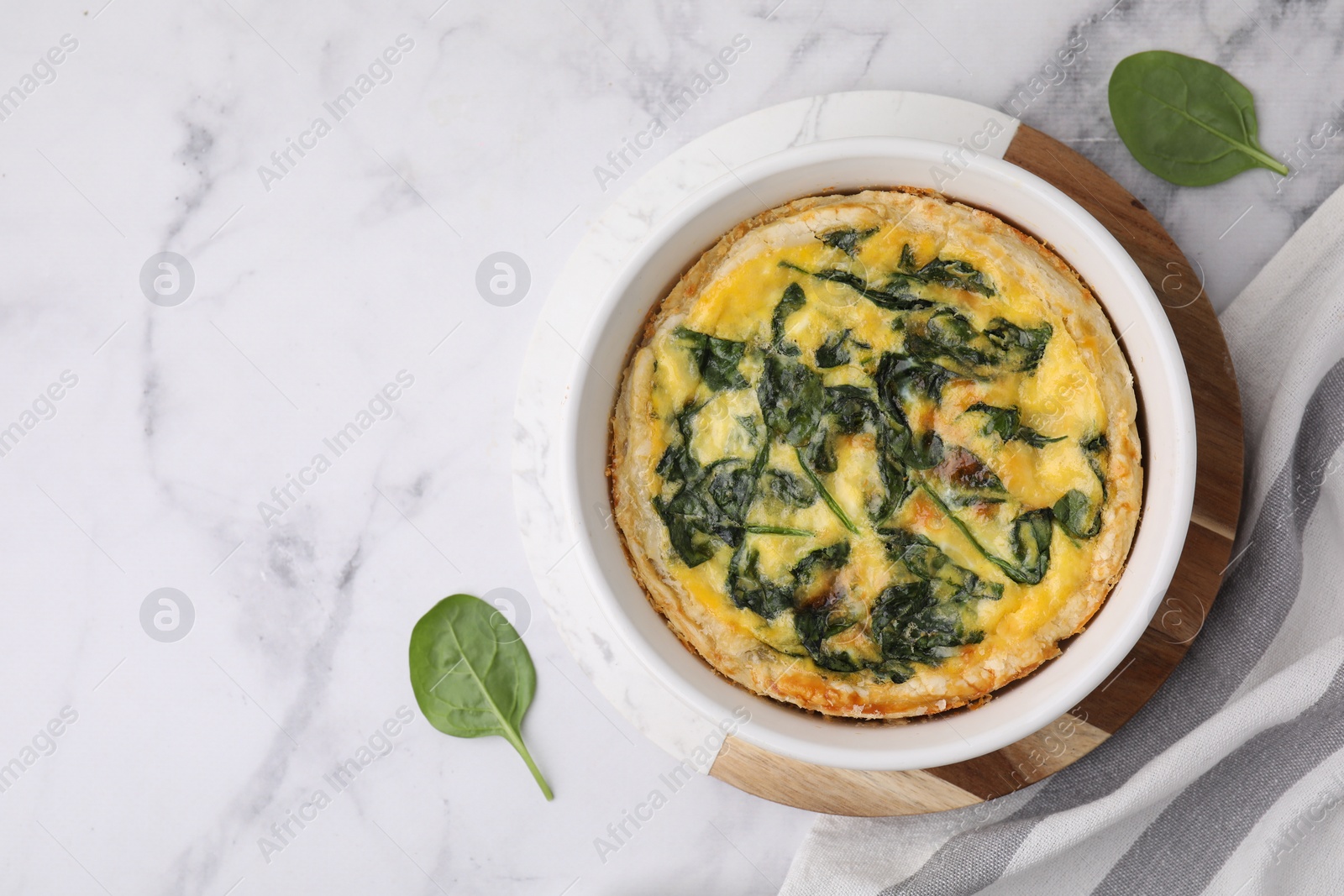 Photo of Delicious pie with spinach on white marble table, flat lay. Space for text