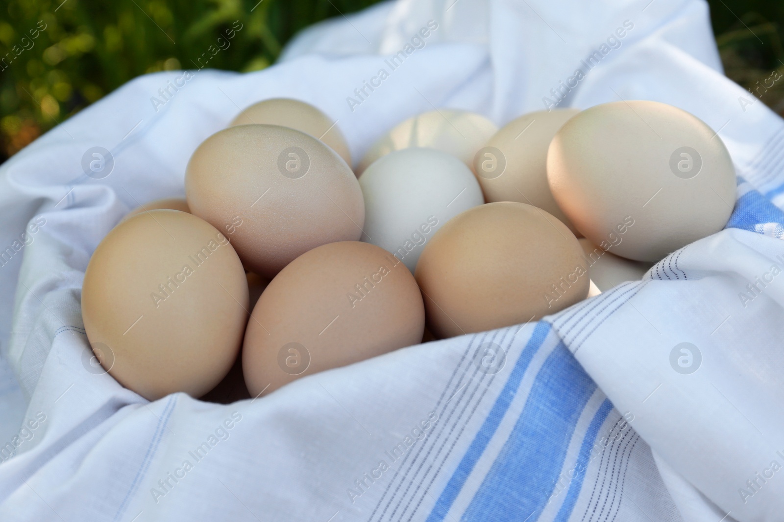 Photo of Fresh raw eggs and fabric in basket, closeup