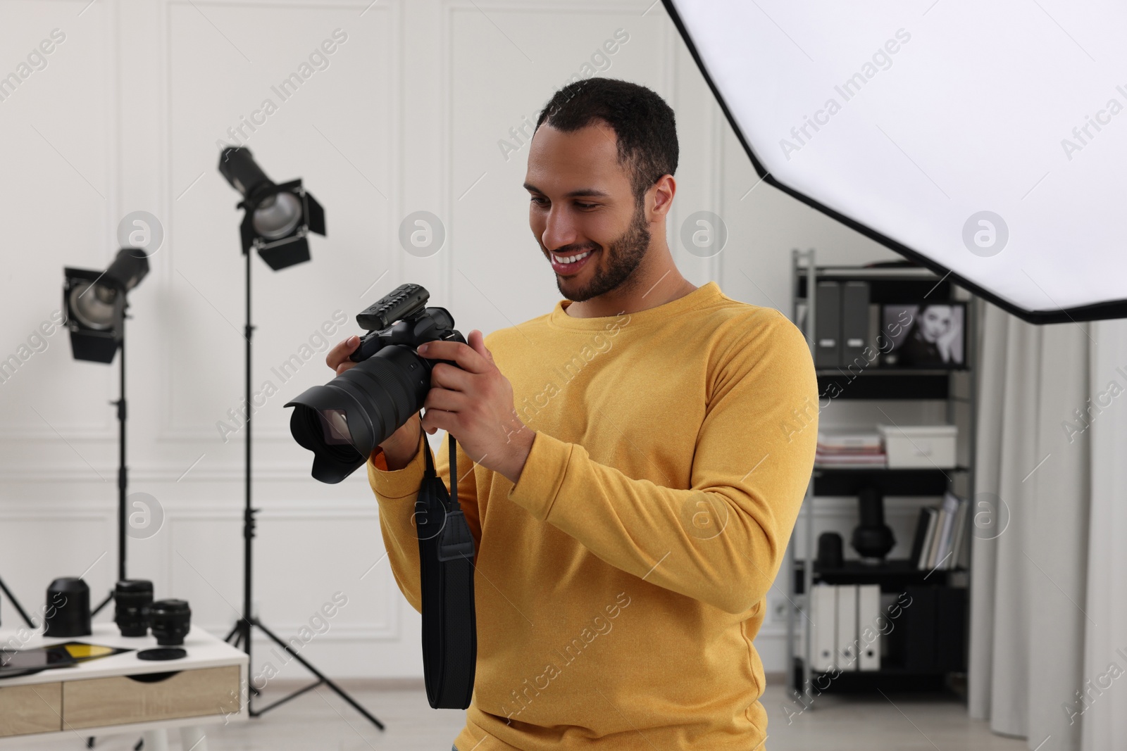 Photo of Young professional photographer with camera in modern photo studio