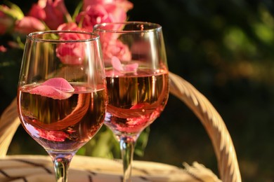Photo of Glassesdelicious rose wine with petals outside. Space for text