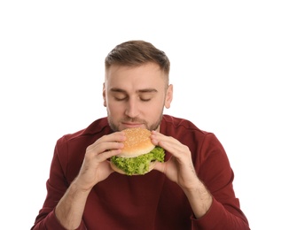 Young man eating tasty burger on white background